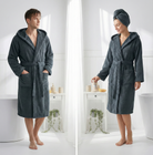 Two people wearing dark gray hooded robes in a bathroom setting.