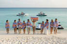 Group of people on a beach with some in the water, wrapped in colorful towels.