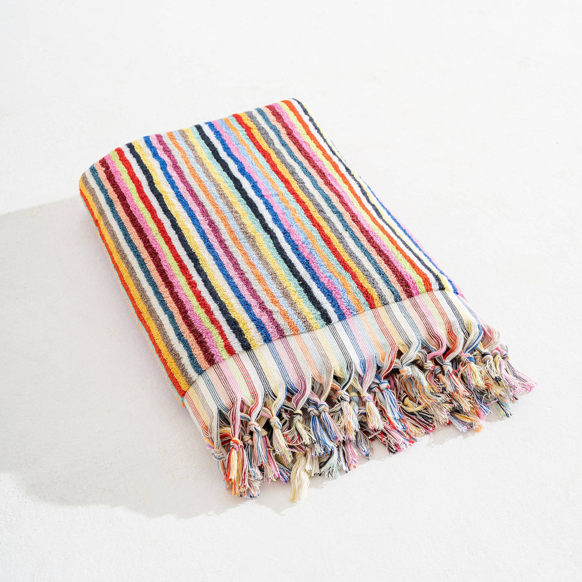 Multicolored striped towel with tassels on a white surface