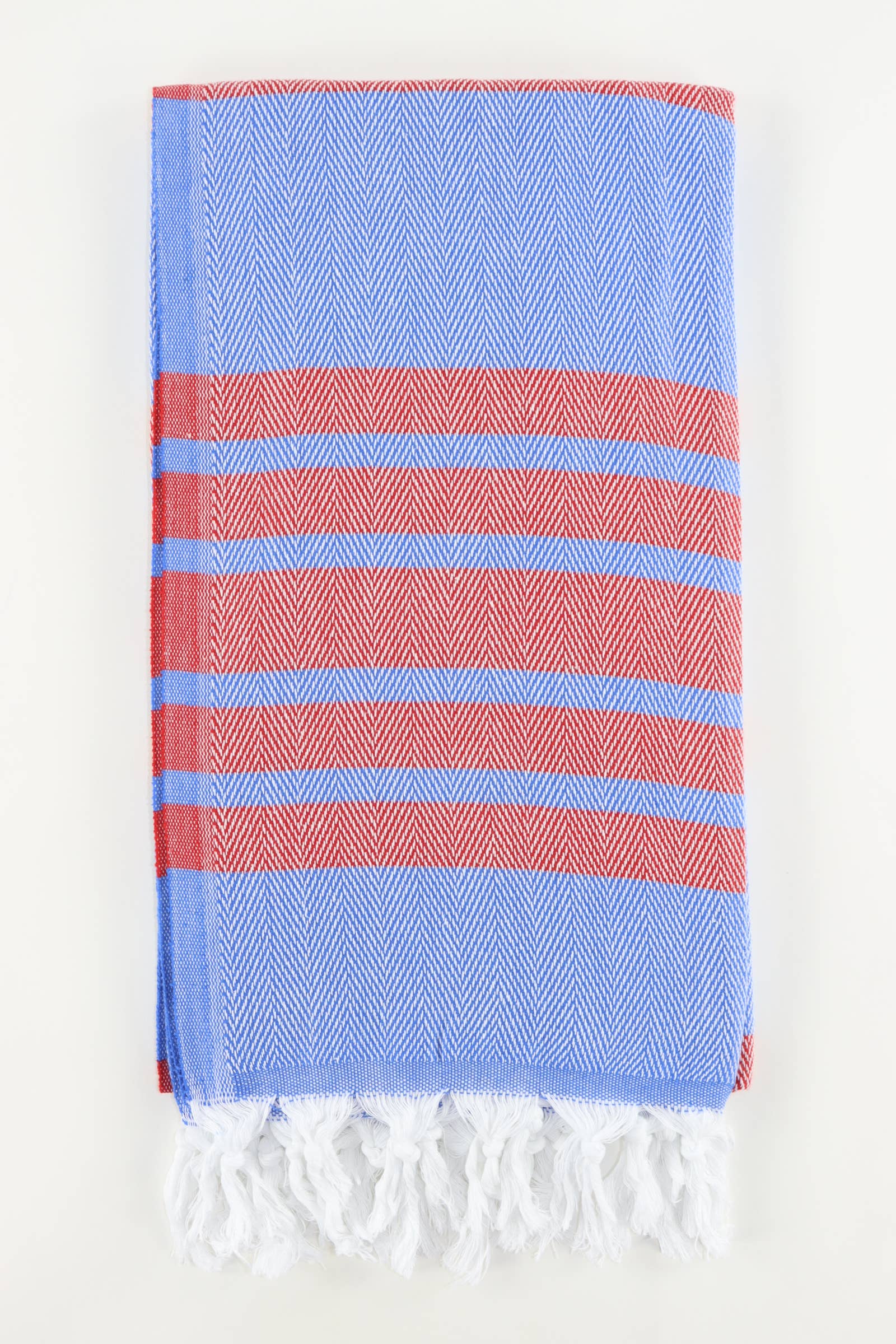 A stack of folded Turkish towels in various solid colors including green, blue, pink, red, gray, and white, displaying the herringbone texture.