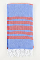 A stack of folded Turkish towels in various solid colors including green, blue, pink, red, gray, and white, displaying the herringbone texture.