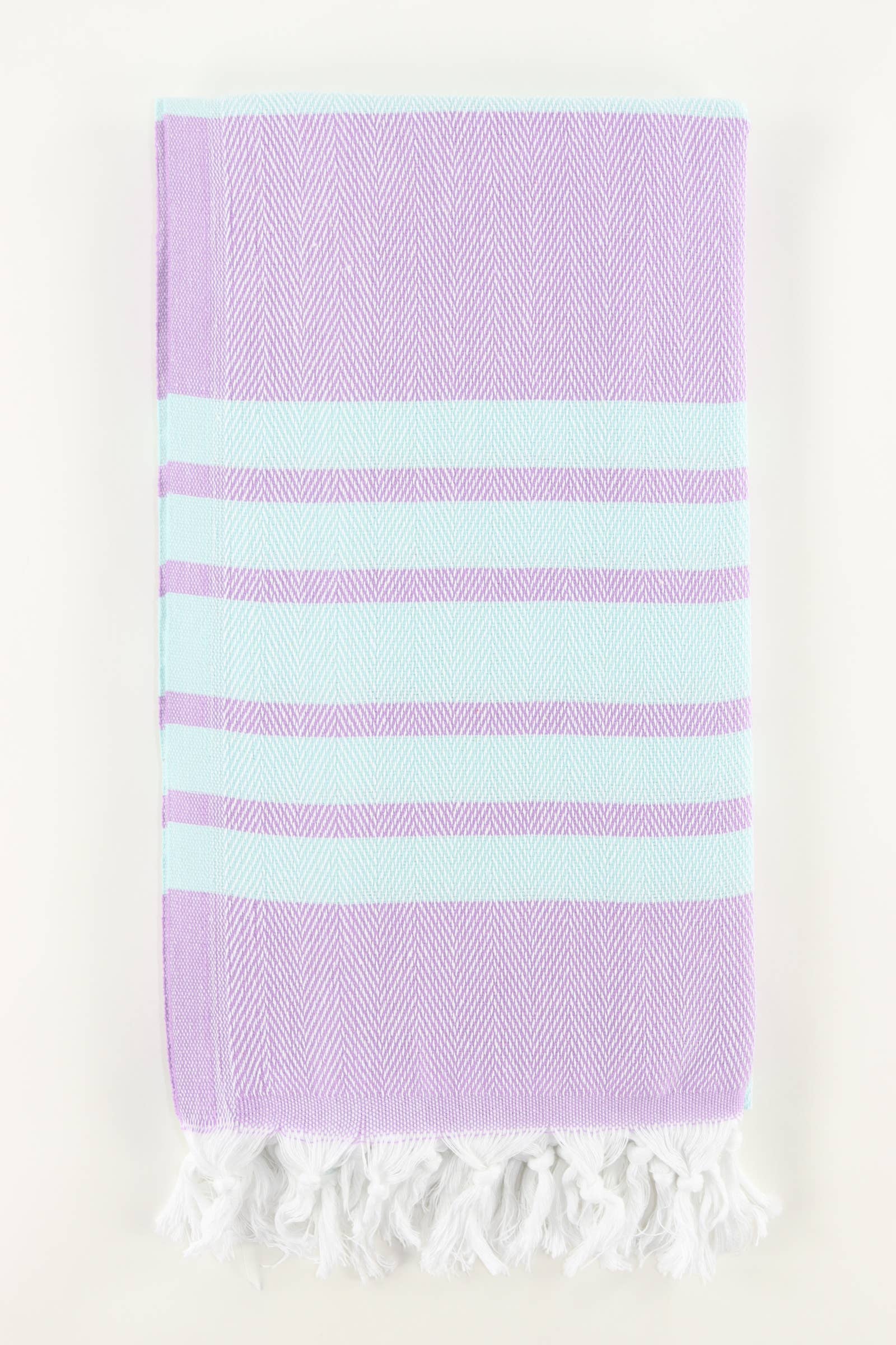 A stack of folded Turkish towels in various solid colors including green, blue, pink, red, gray, and white, displaying the herringbone texture.