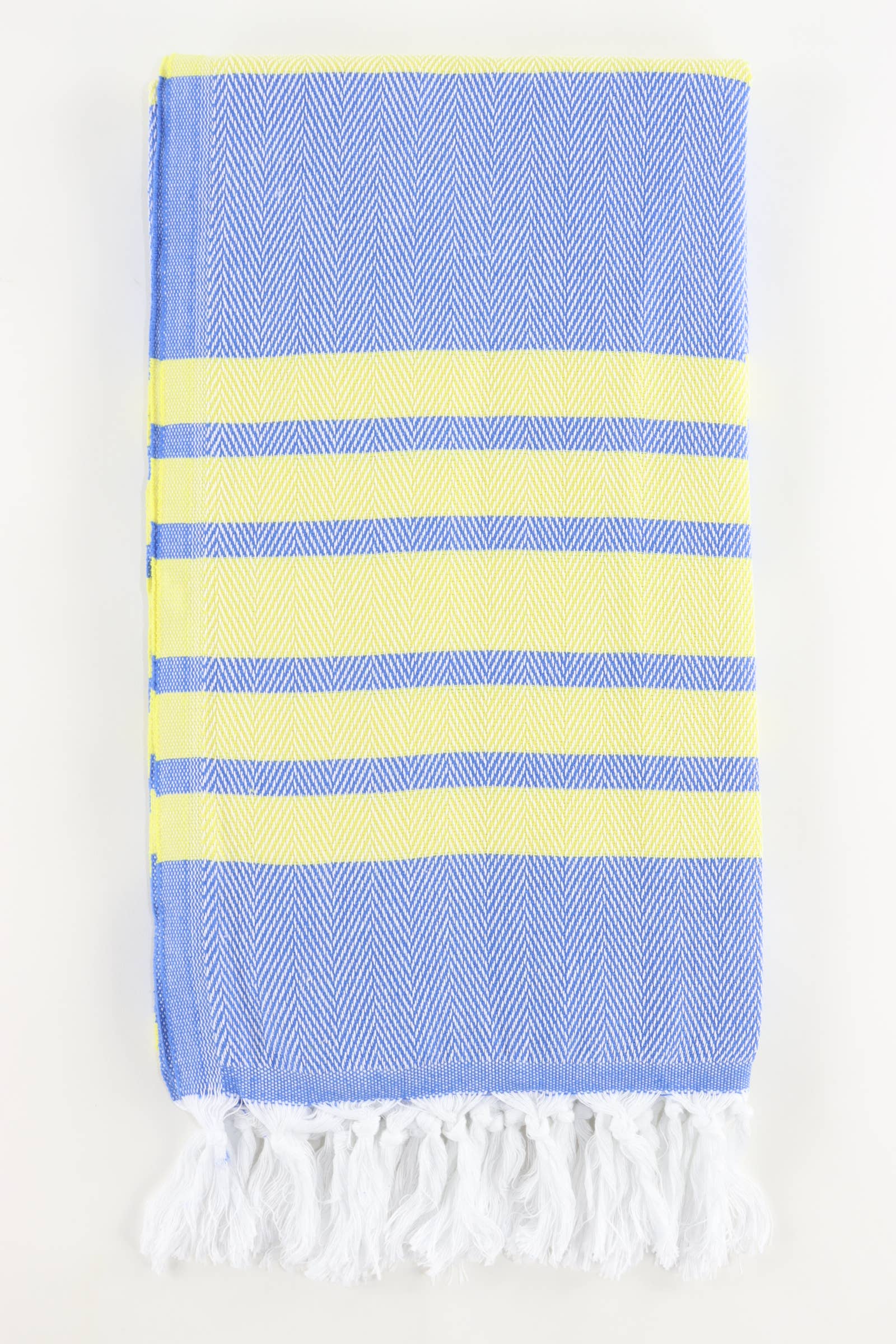A stack of folded Turkish towels in various solid colors including green, blue, pink, red, gray, and white, displaying the herringbone texture.