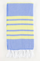A stack of folded Turkish towels in various solid colors including green, blue, pink, red, gray, and white, displaying the herringbone texture.