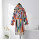 A multicolor striped knit hooded robe with a tie belt and tassel fringe, displayed on a mannequin in a bright white bathroom setting.