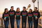 Group of six friends wearing hoodies with 'My Life Runs on Salty' text, standing on a wooden boardwalk by the beach.